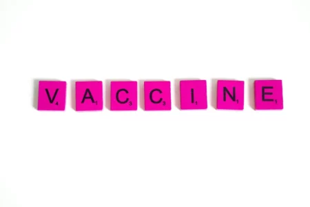 Pink letter tiles on a white background spelling out the word "FLU VACCINE."
